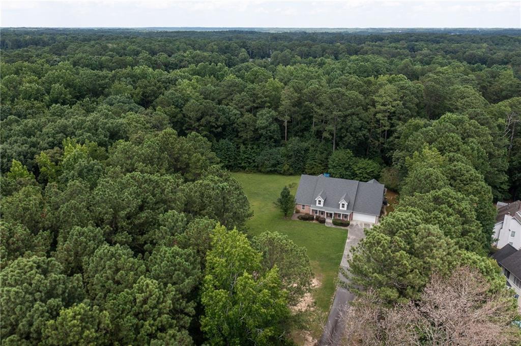 Aerial view of a house and large lawn surrounded by dense woodland.