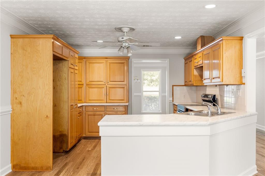 Kitchen with honey-colored cabinets, a large white island sink, and wood flooring.