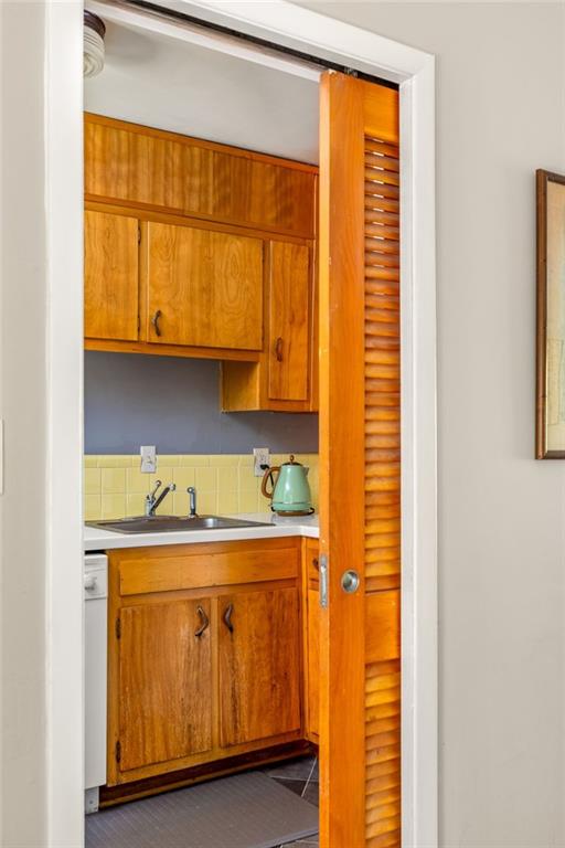Kitchen with honey-toned wood cabinets, yellow tile backsplash, and a louvered sliding door.