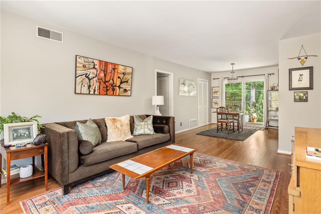 Living room with a brown sofa, colorful patterned rug, and dining area by glass doors.