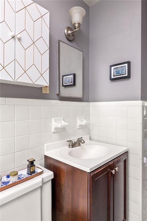 Bathroom vanity with a white sink, dark wood cabinet, and white tiled walls.