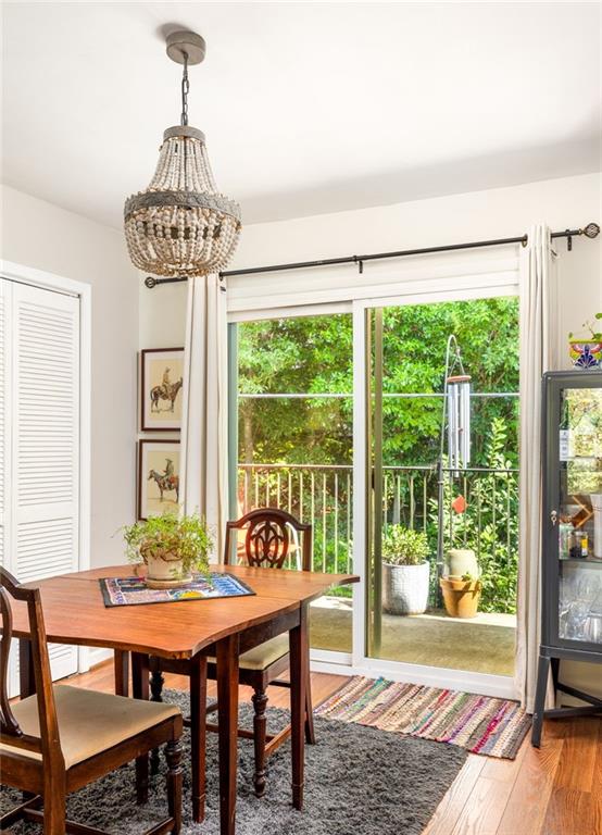 Dining room with a wooden table and chandelier beside sliding glass doors overlooking greenery.