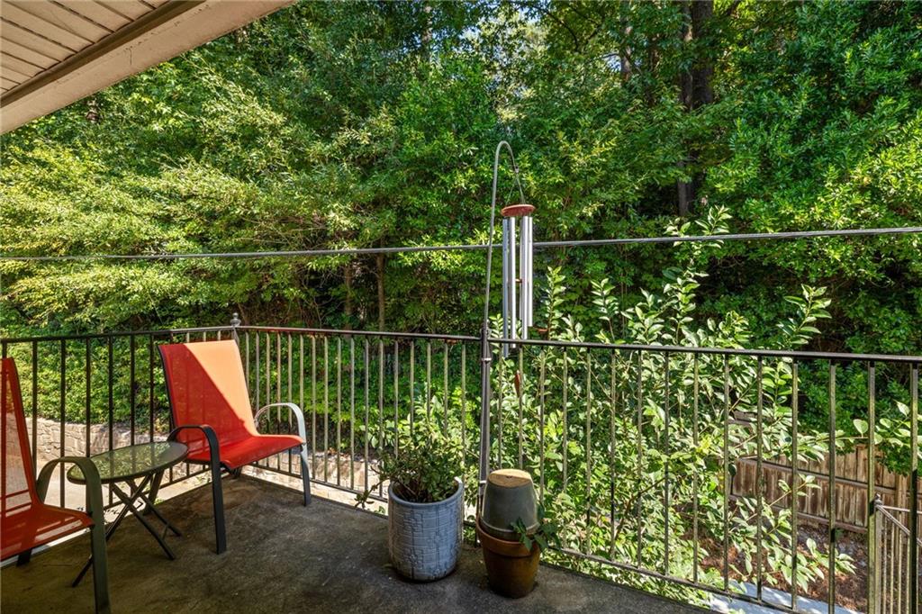 Covered patio with red chairs and potted plants overlooking dense woodland.
