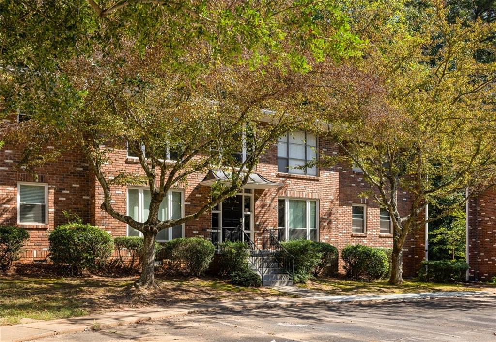 Red-brick residential building framed by autumn trees, with steps leading to the entrance.