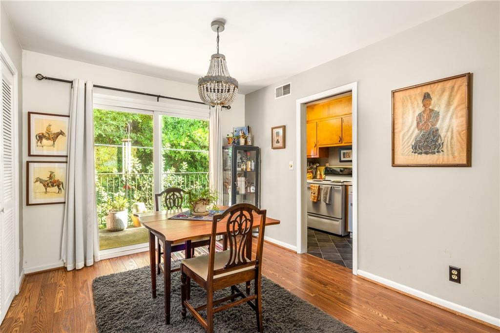 Dining room with a wooden table, chandelier, hardwood floors, and glass doors opening to greenery.