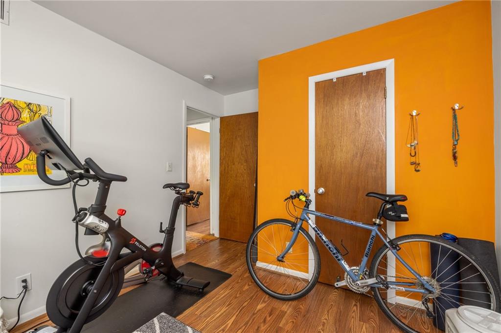 Exercise room with a stationary bike, road bicycle, and vivid orange accent wall.