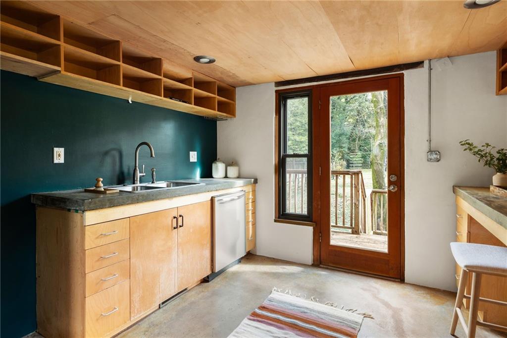 Kitchen with teal backsplash, wood cabinetry, and a glass door opening to a deck.