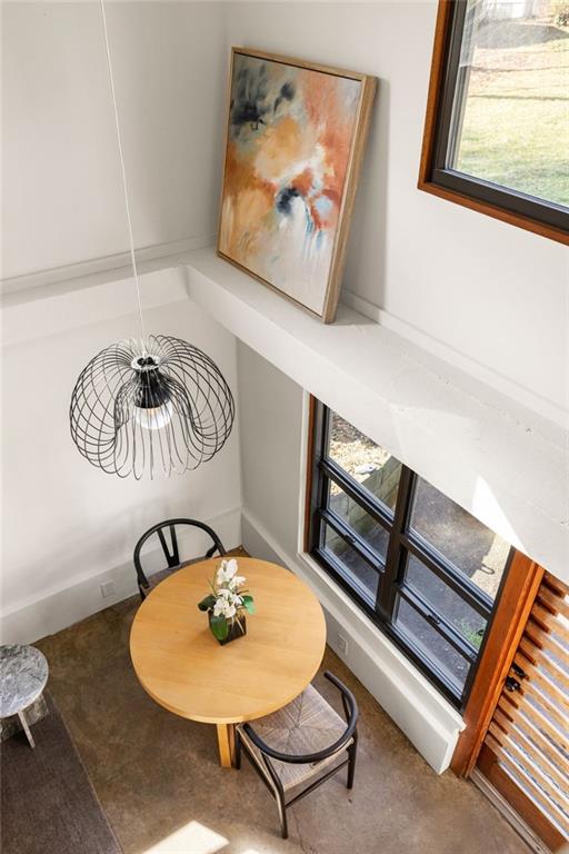 Dining area with a round wooden table beneath a sculptural pendant and tall windows.
