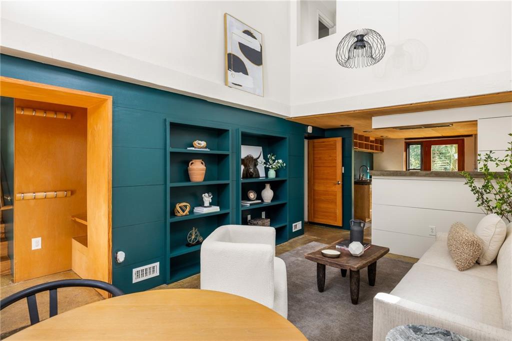 Living room with teal built-in shelves, white seating, and an open kitchen beyond.