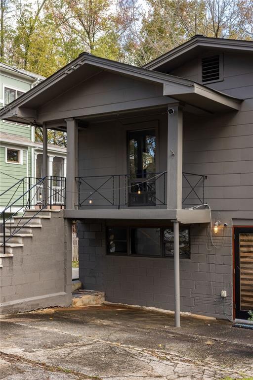 Gray house exterior with a raised covered porch, dark railings, and driveway.