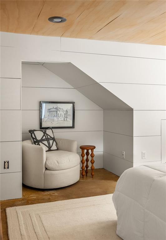 Bedroom with a reading nook beneath a sloped ceiling and a rounded cream armchair.