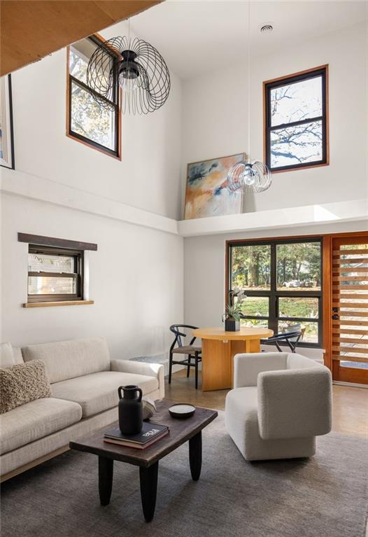 Living room with vaulted ceiling, upper windows, light sofa, and dining nook.