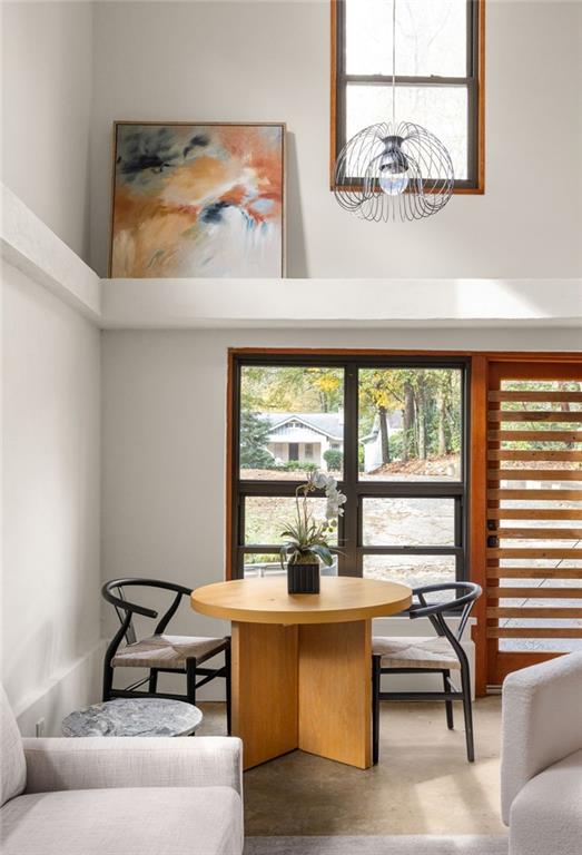 Dining nook with a round wood table, black chairs, and tall windows.