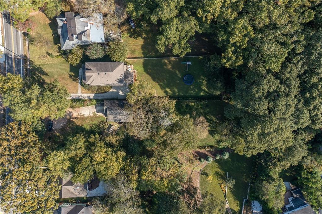 Aerial view of a home with a fenced, tree-lined backyard and trampoline.