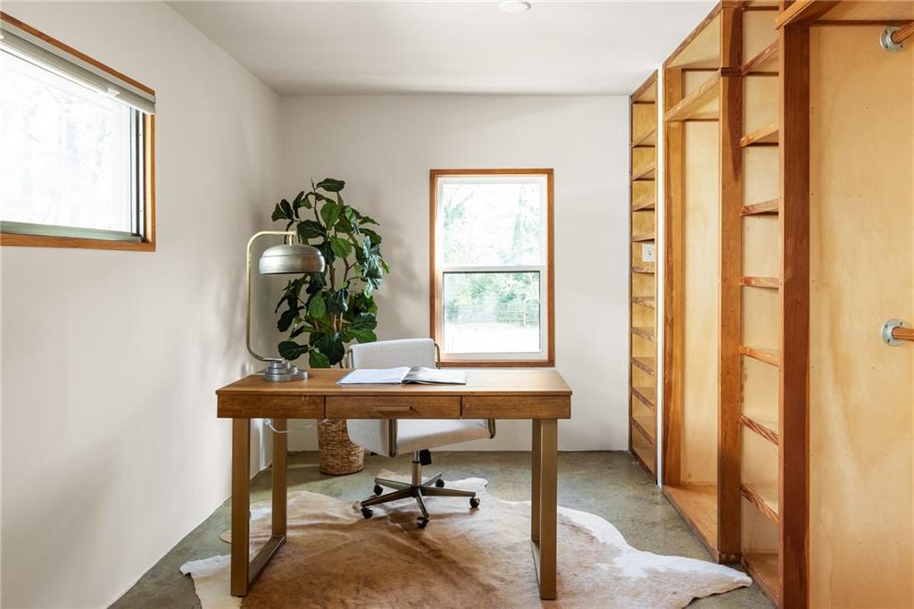 Home office with built-in wooden shelving, a desk, and two windows.