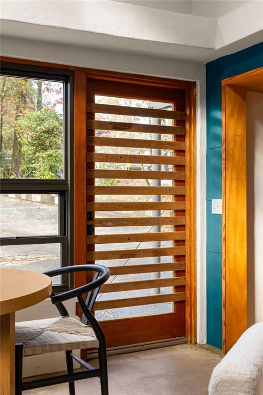Interior with a wooden slatted glass door, teal wall, and chair beside a window.