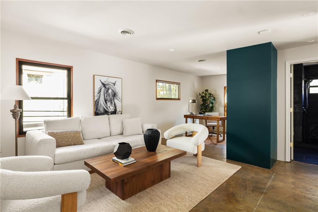 Staged living room with white seating, a wooden coffee table, and a bold teal accent wall.