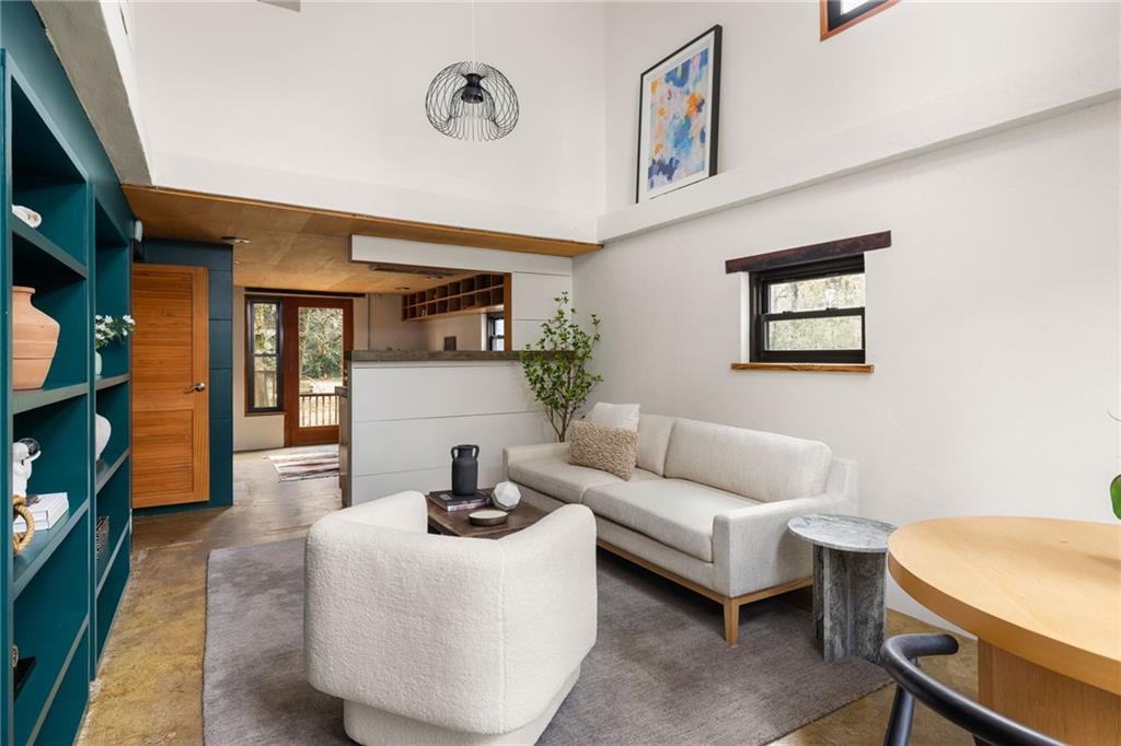 Living room with teal built-in shelves, white seating, and a high ceiling.