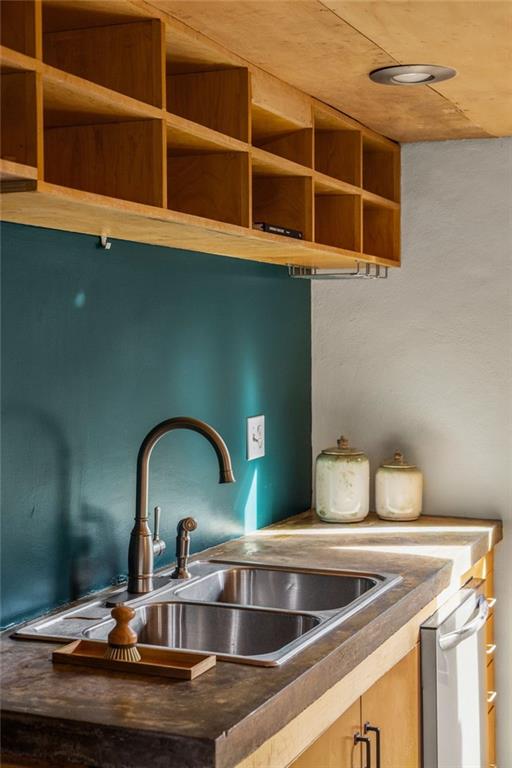 Kitchen sink with a teal backsplash, dark stone counter, and open wooden shelves.