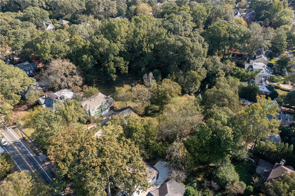 Aerial view of a wooded residential property surrounded by homes and mature trees.
