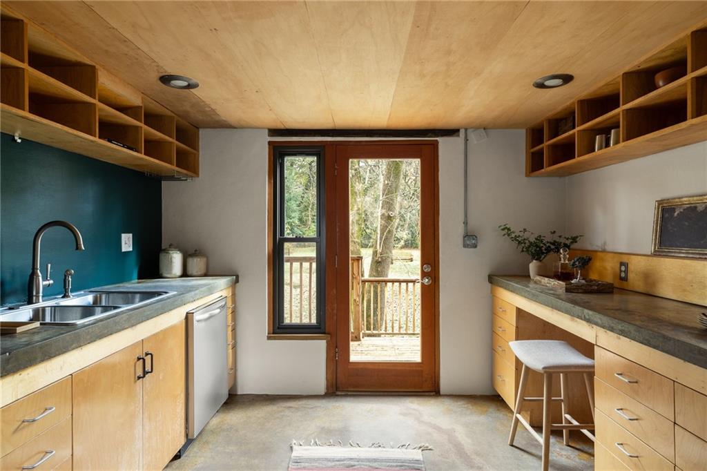 Kitchen with wood cabinetry, open shelving, and a glass door leading to a deck.