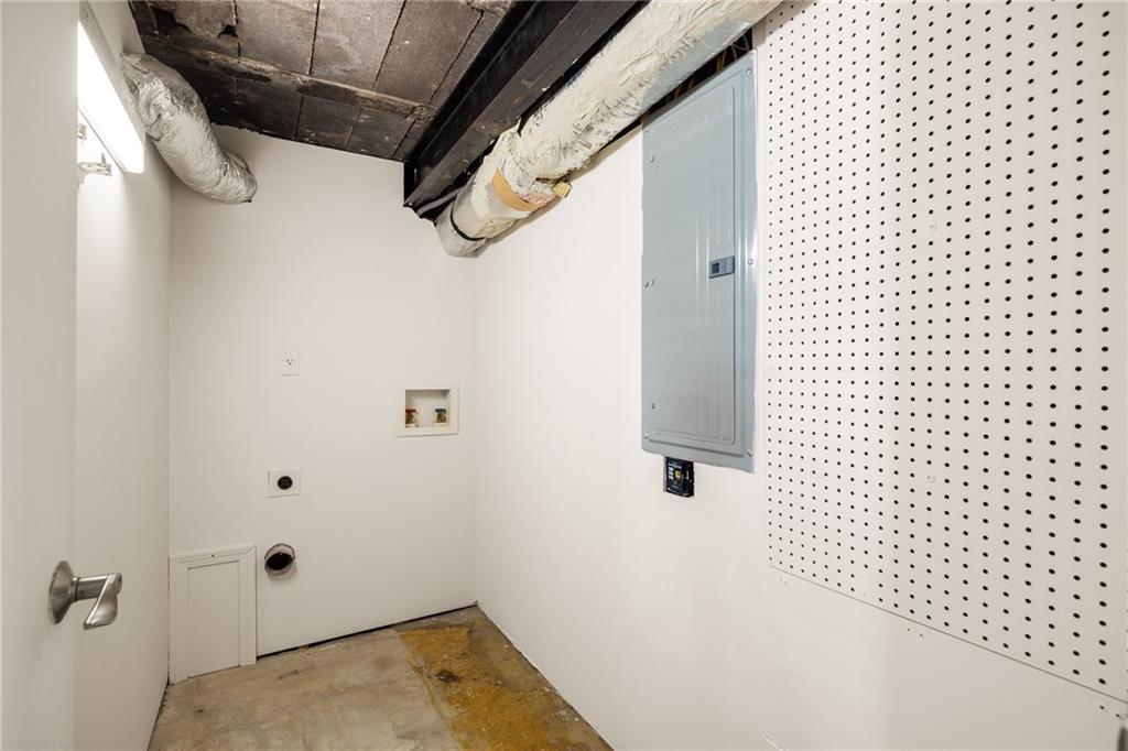 Utility room with exposed ducts, an electrical panel, and a wall of pegboard.
