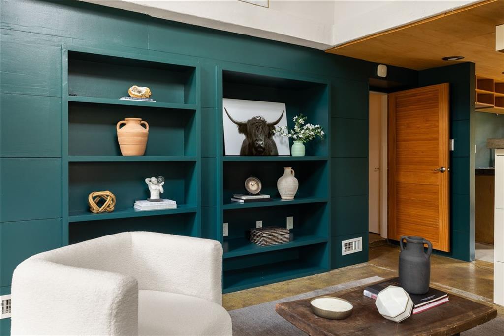 Living room with deep teal built-in shelves, a white chair, and a wooden coffee table.