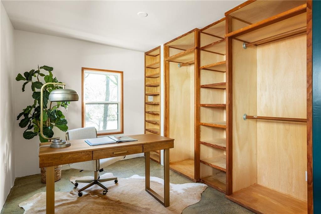 Home office with a wooden desk and extensive built-in shelving and wardrobe storage.