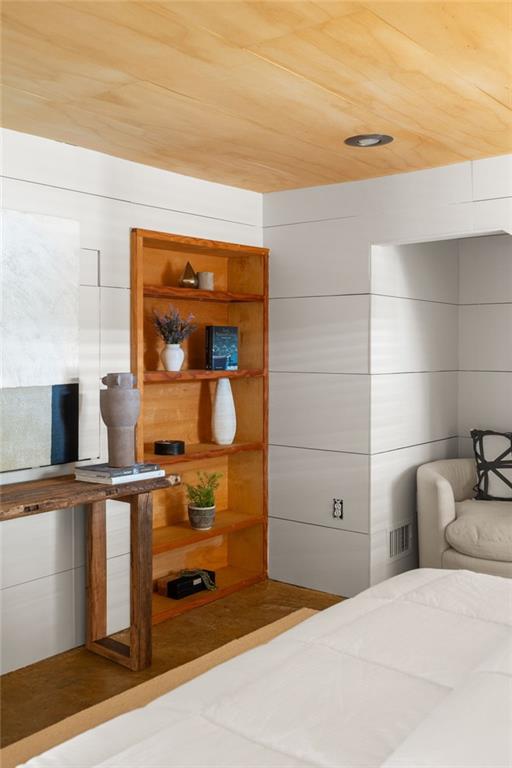 Bedroom with a wood-paneled ceiling, built-in wooden shelves, and a white bed.