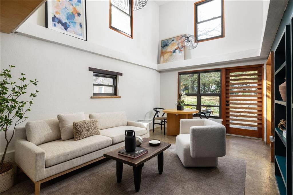 Double-height living room with a cream sofa, upper windows, and a wood-slat door.