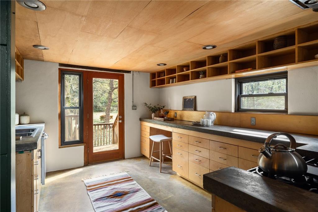 Kitchen with wood cabinetry, open shelving, and a glass door to the deck.