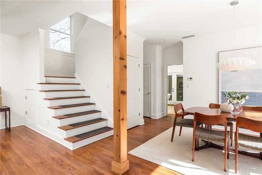 Dining area beside a white staircase with dark wood treads and a timber support post.
