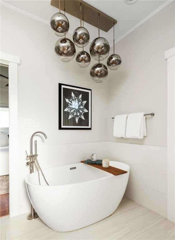Modern bathroom with a freestanding tub beneath reflective globe pendant lights.
