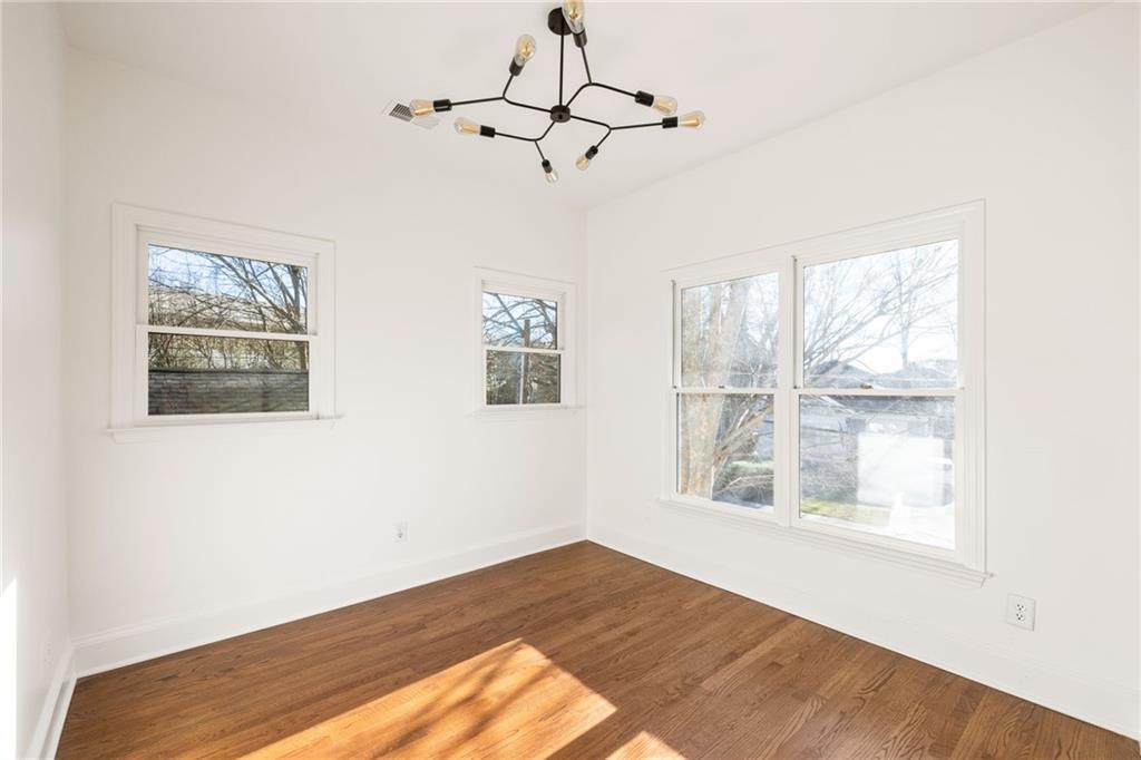 Vacant room with hardwood floors, multiple windows, and a modern branching ceiling light.