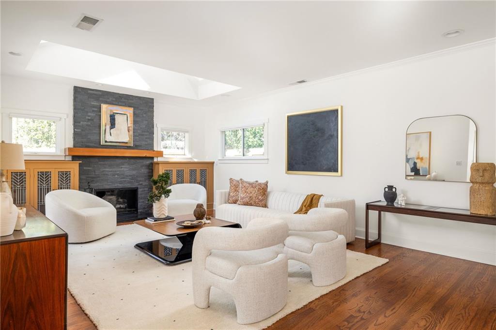 Living room with a dark stone fireplace, built-in wood cabinets, white seating, and a large skylight.