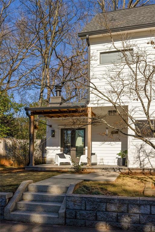 Rear of a white two-story house with a covered patio and steps to the yard.