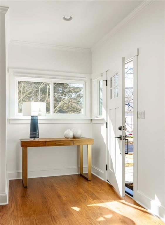 Bright entryway with hardwood floors, a console table, and an open front door.
