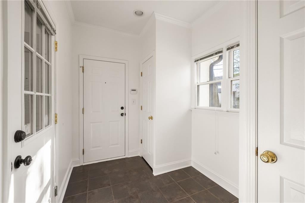 Unfurnished entry foyer with white doors, windows, and dark tile flooring.