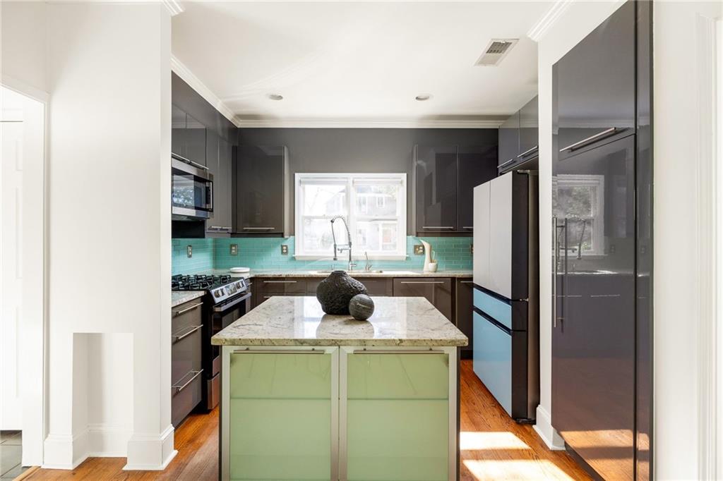 Kitchen with turquoise tile backsplash, dark cabinets, and a pale stone island.