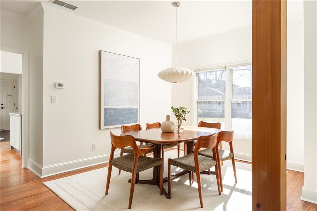 Dining room with a wooden table, sculptural pendant light, and large windows.