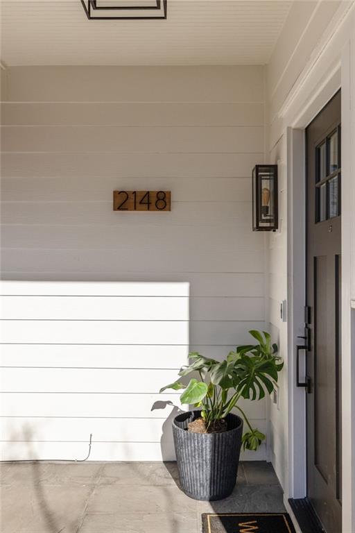 Covered front entry with a dark door, 2148 address plaque, and potted plant.