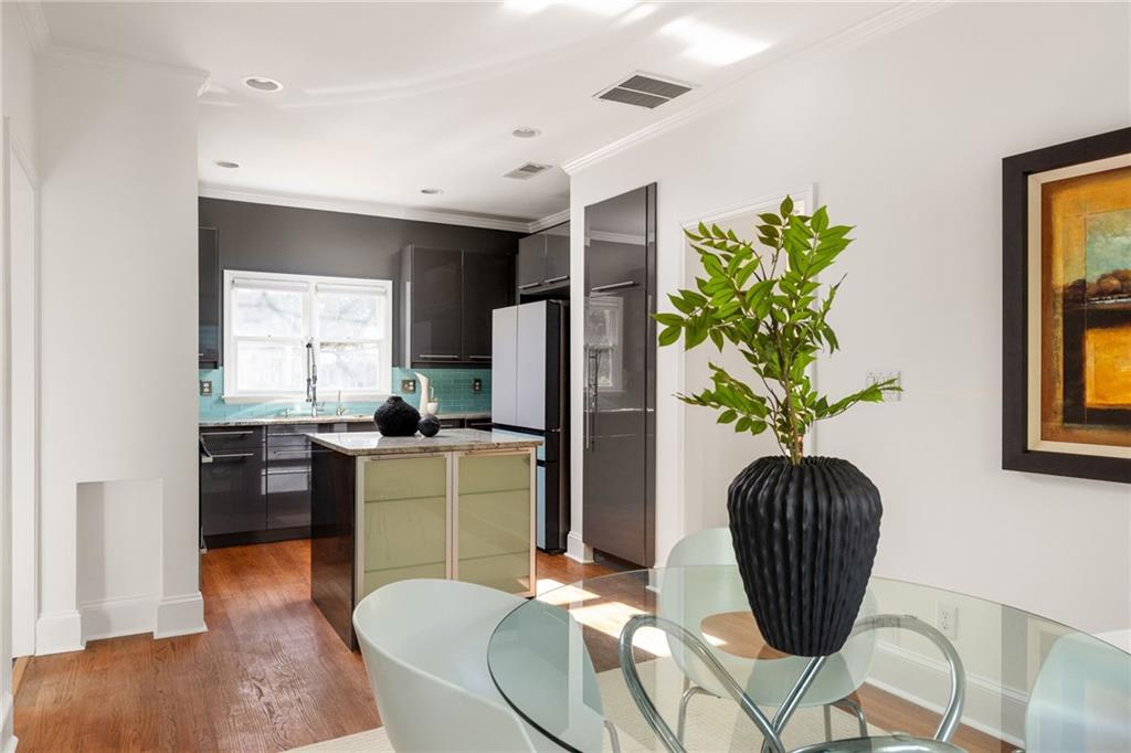 Kitchen and dining area with dark cabinets, turquoise backsplash, central island, and glass table.