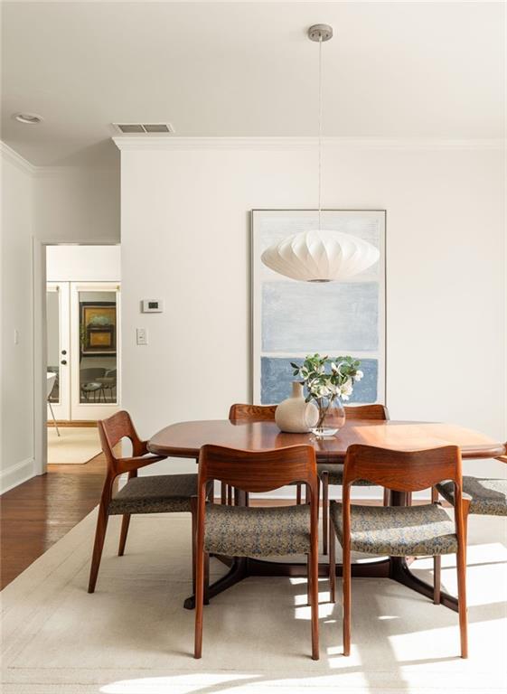 Dining room with a round wooden table, matching chairs, sculptural pendant, and abstract wall art.