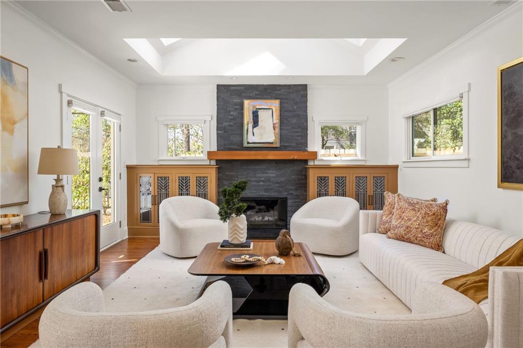 Living room with a stone fireplace, built-in cabinetry, and white upholstered seating.