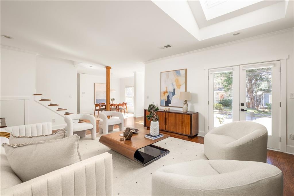 Bright living room with a white sectional, sculptural chairs, and glass doors to the yard.
