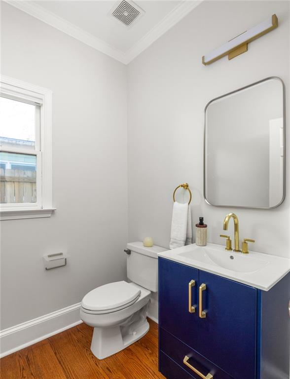 Bathroom with a navy-blue vanity, brass fixtures, and warm wood flooring.