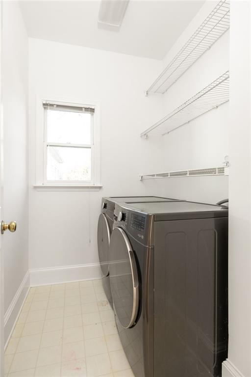 Laundry room with front-loading washer and dryer, wire shelves, and a window.