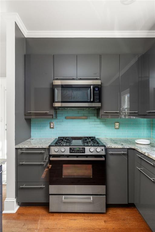 Kitchen with dark gray cabinets, turquoise tile backsplash, and stainless steel gas range.