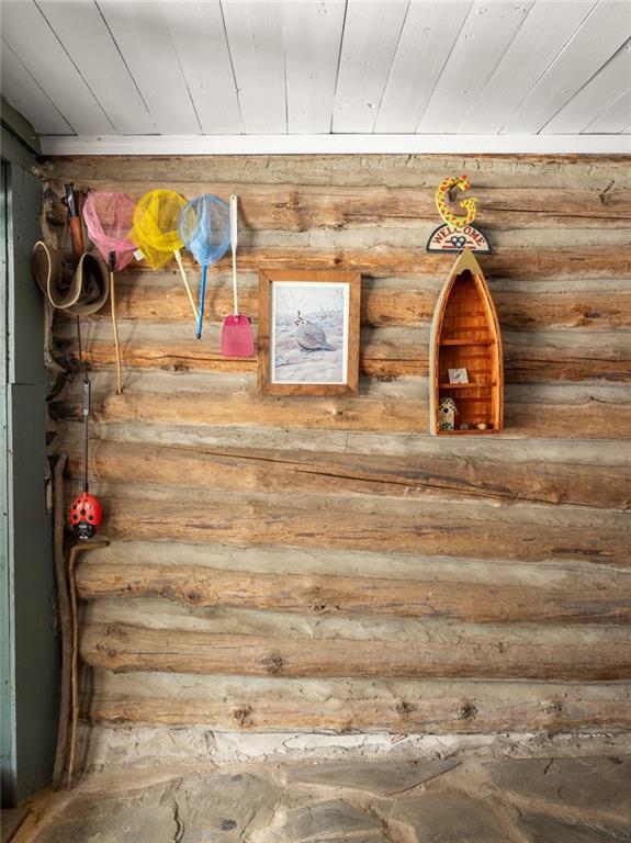 Rustic log wall decorated with colorful fishing nets, a framed fish picture, and a canoe-shaped shelf.