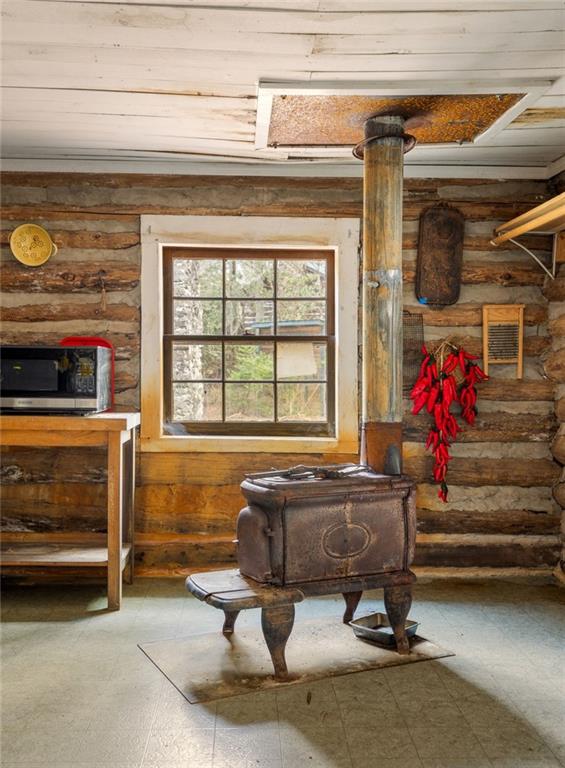 Rustic log cabin kitchen with a cast-iron stove, exposed log walls, and a window.